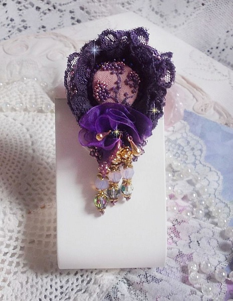 Broche Lady Romantique brod&eacute;e avec une dentelle violine ann&eacute;e 1950 avec un tissu en lin vieux rose brod&eacute; de fleurs et branches en rocailles bord&eacute; d&rsquo;un ruban organza, fleurs, cristaux et breloques