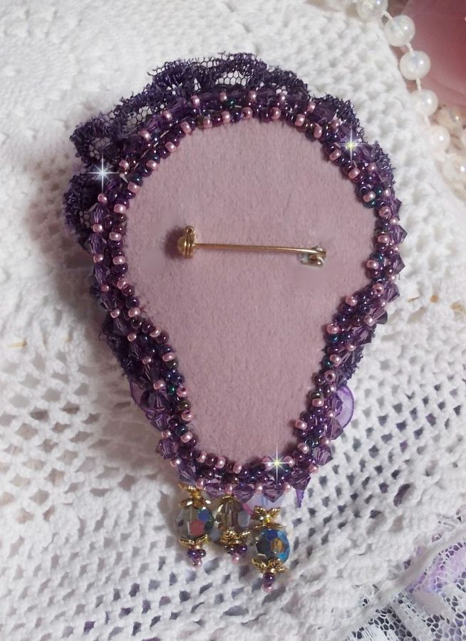 Broche Lady Romantique brod&eacute;e avec une dentelle violine ann&eacute;e 1950 avec un tissu en lin vieux rose brod&eacute; de fleurs et branches en rocailles bord&eacute; d&rsquo;un ruban organza, fleurs, cristaux et breloques