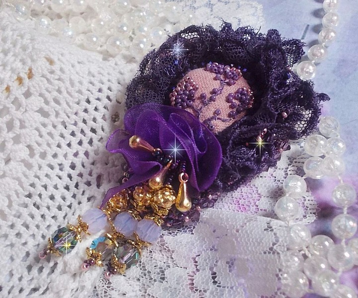 Broche Lady Romantique brod&eacute;e avec une dentelle violine ann&eacute;e 1950 avec un tissu en lin vieux rose brod&eacute; de fleurs et branches en rocailles bord&eacute; d&rsquo;un ruban organza, fleurs, cristaux et breloques