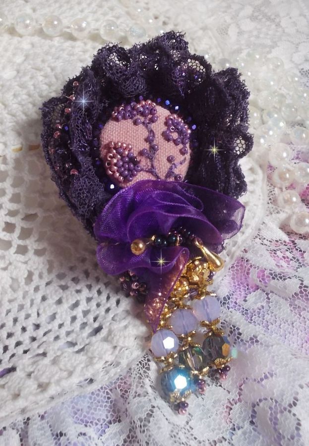 Broche Lady Romantique brod&eacute;e avec une dentelle violine ann&eacute;e 1950 avec un tissu en lin vieux rose brod&eacute; de fleurs et branches en rocailles bord&eacute; d&rsquo;un ruban organza, fleurs, cristaux et breloques