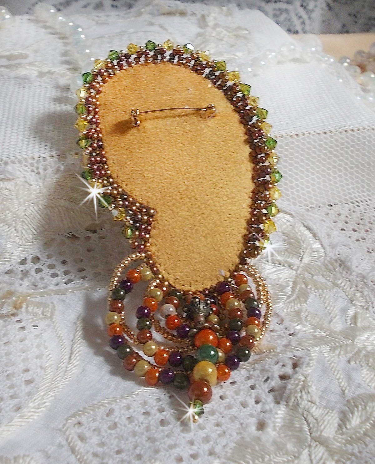 Broche Lune V&eacute;nitienne brod&eacute;e avec un ruban de soie orange, vert et jaune, cristaux, : toupies et chatons. S&rsquo;ajoute &agrave; l&rsquo;ensemble des perles magiques et rocailles sur une broche Dor&eacute; 