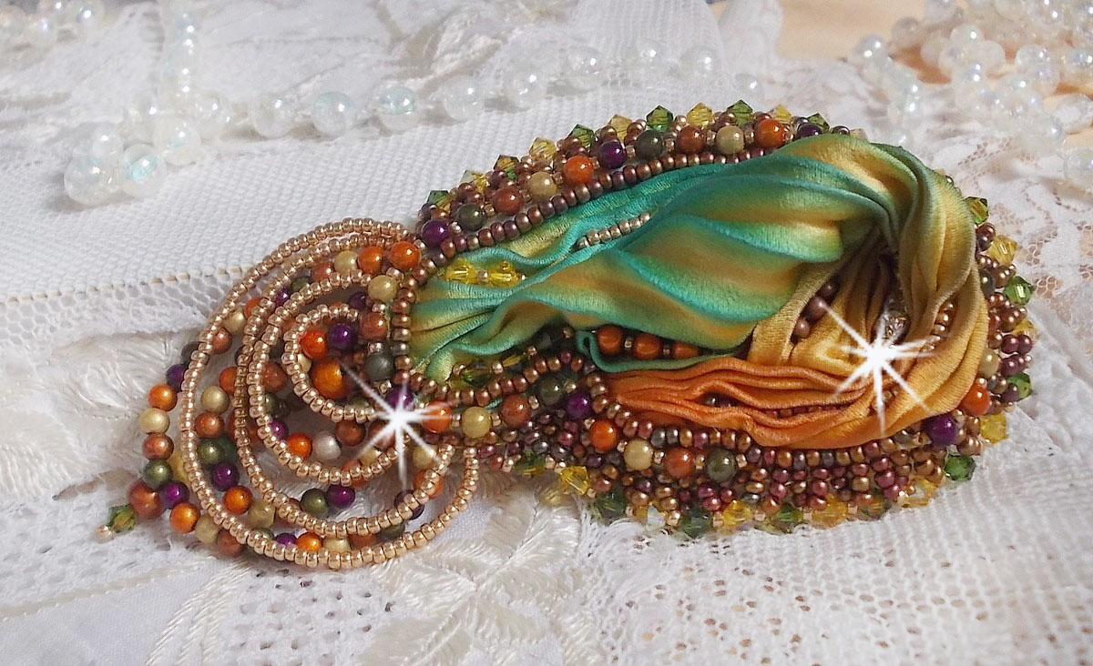 Broche Lune V&eacute;nitienne brod&eacute;e avec un ruban de soie orange, vert et jaune, cristaux, : toupies et chatons. S&rsquo;ajoute &agrave; l&rsquo;ensemble des perles magiques et rocailles sur une broche Dor&eacute; 