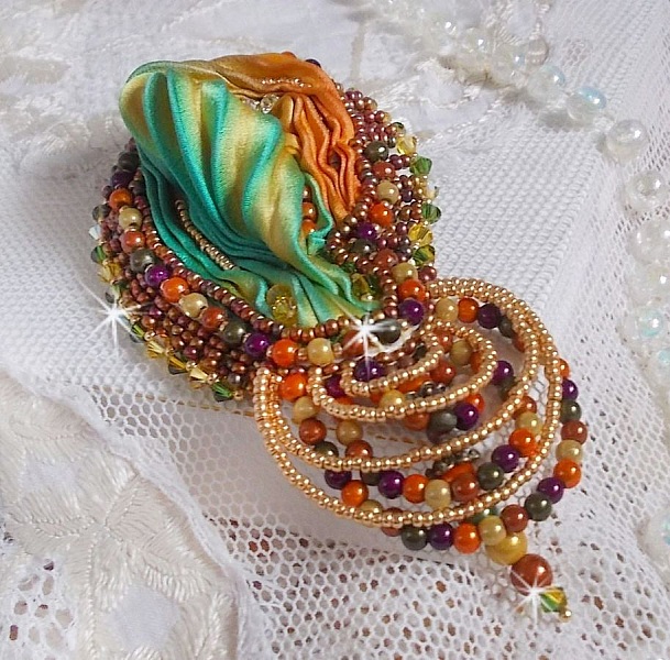 Broche Lune V&eacute;nitienne brod&eacute;e avec un ruban de soie orange, vert et jaune, cristaux, : toupies et chatons. S&rsquo;ajoute &agrave; l&rsquo;ensemble des perles magiques et rocailles sur une broche Dor&eacute; 