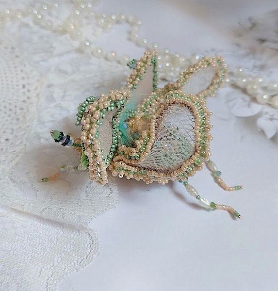 Broche artisanale en forme d'insecte brodée de perles délicates.