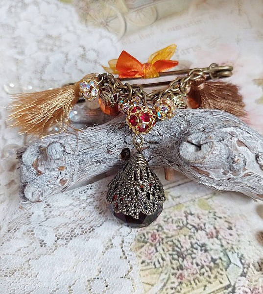 Broche artisanale Méline des Bois avec strass, pompons et breloques.