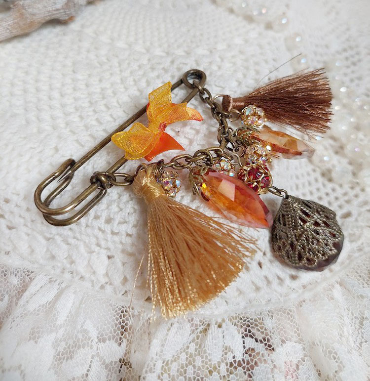 Broche artisanale automnale avec strass, pompons et gouttes verre.