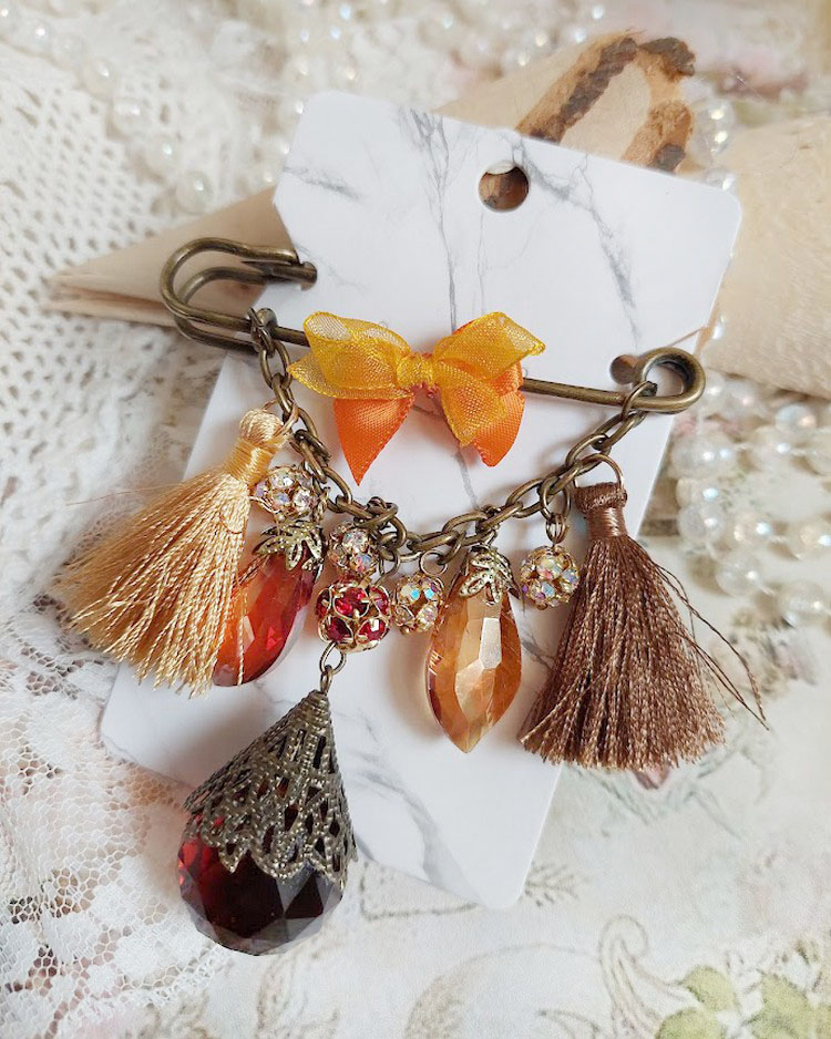 Broche artisanale automnale avec pompons, strass et gouttes verre.