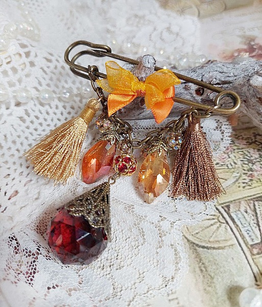Broche épingle bohème avec strass, pompons et perles colorées.