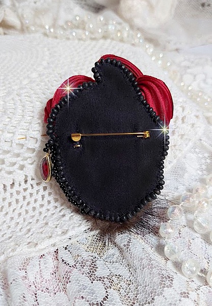 Broche Rouge et Noir brod&eacute;e avec un ruban de soie de couleur Rouge Fonc&eacute; &agrave; laquelle s&rsquo;ajoute des toupies Siam AB , perles rondes facett&eacute;es aplaties Antique Noires et goutte sur un support Dor&eacute;