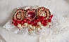 Broche Rubis brod&eacute;e avec trois cabochons Ivoire et Rouge &agrave; laquelle s&rsquo;ajoute des toupies aux couleurs Cristal, Burgundy et Garnet, des perles nacr&eacute;es et opaque. Mont&eacute; sur une dentelle et une broche