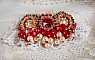 Broche Rubis brod&eacute;e avec trois cabochons Ivoire et Rouge &agrave; laquelle s&rsquo;ajoute des toupies aux couleurs Cristal, Burgundy et Garnet, des perles nacr&eacute;es et opaque. Mont&eacute; sur une dentelle et une broche