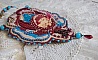 Collier brodé artisanal avec cabochon vintage et perles colorées.
