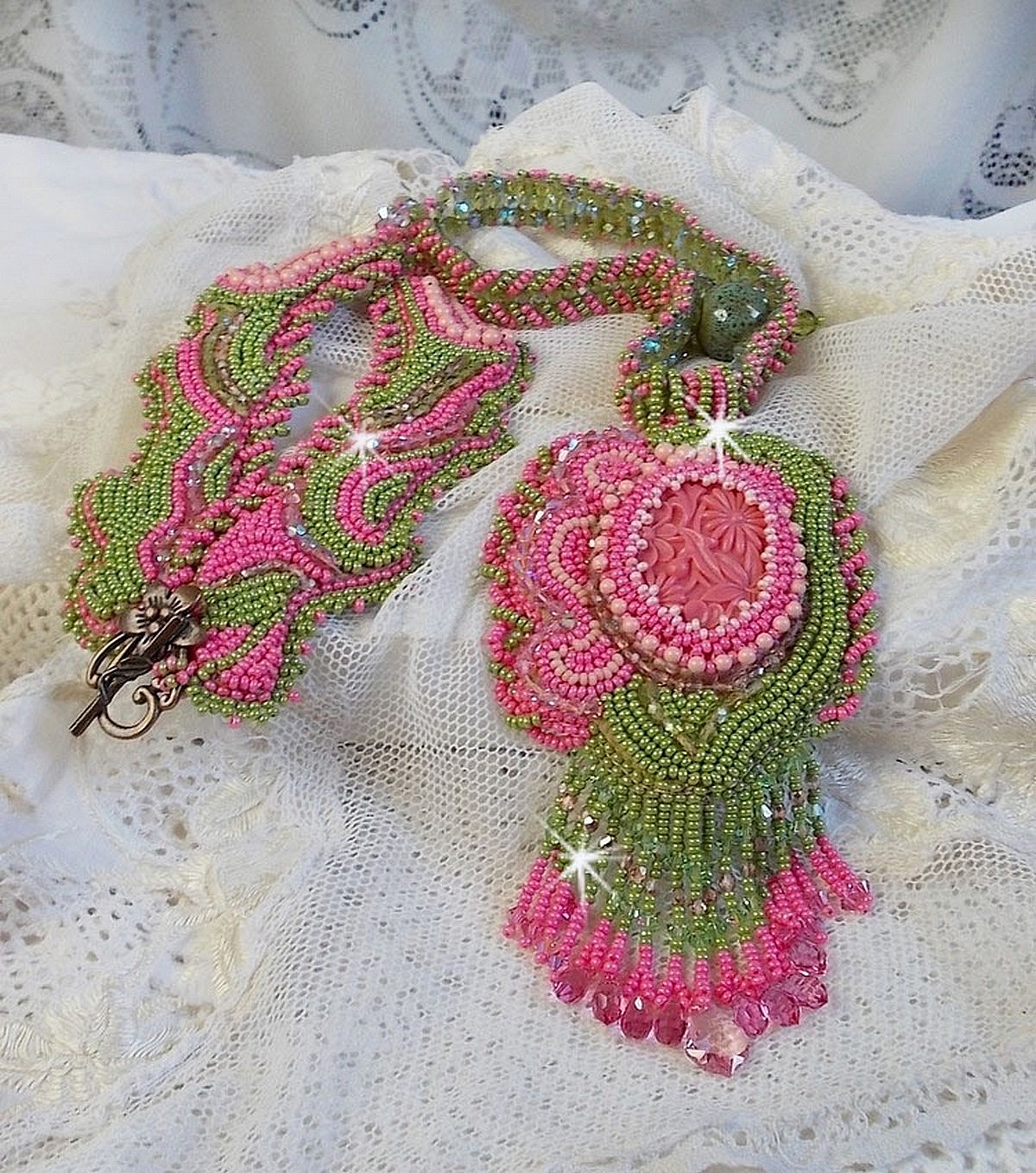 Collier Miss Lady brod&eacute; avec un cabochon repr&eacute;sentant des fleurs de couleur Rose Pink &agrave; laquelle s'ajoute perles rondes, toupies en Cristal, facettes, rocailles Anis, Rose et perle c&eacute;ramique 
