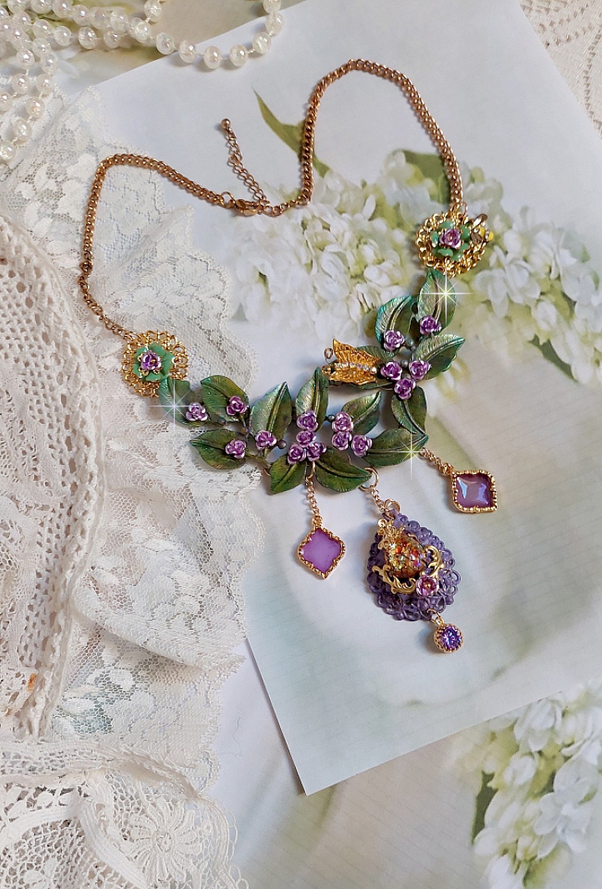 Collier Cam&eacute;lia Japonica mont&eacute; avec un motif feuilles aquarell&eacute;s &agrave; la main, paillettes, breloques papillons et abeille, roses m&eacute;tal, cabochon cristal, pendentifs &eacute;poxy aux couleurs d&rsquo;arc en ciel