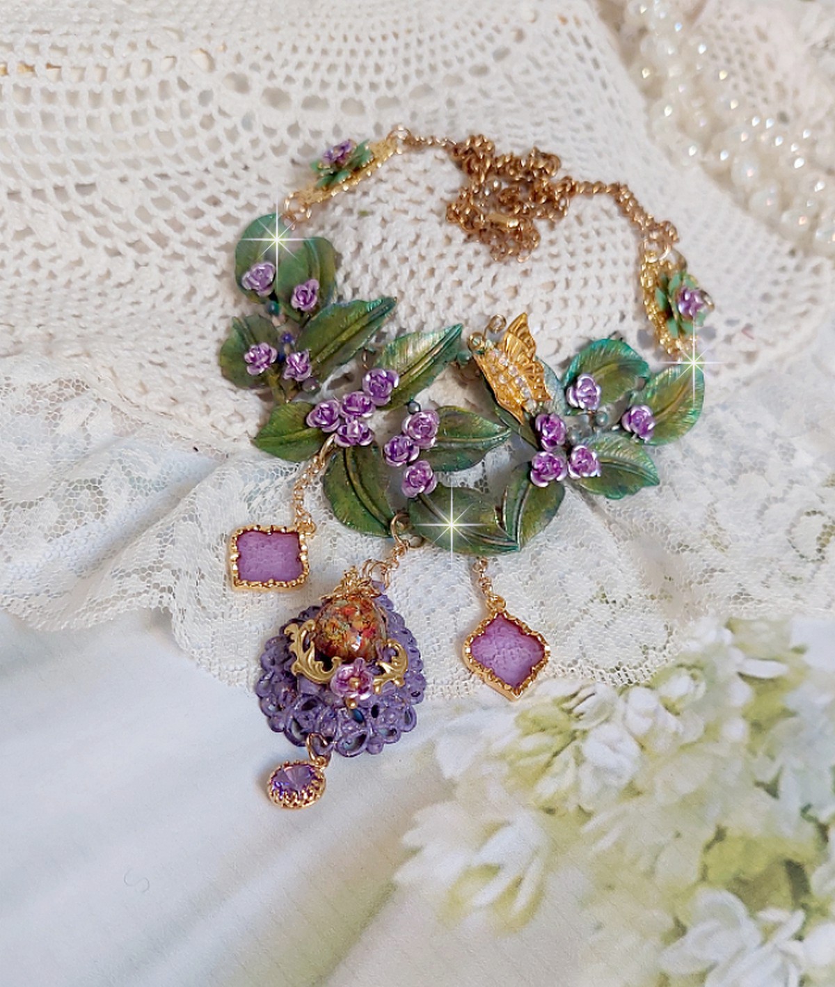 Collier Cam&eacute;lia Japonica mont&eacute; avec un motif feuilles aquarell&eacute;s &agrave; la main, paillettes, breloques papillons et abeille, roses m&eacute;tal, cabochon cristal, pendentifs &eacute;poxy aux couleurs d&rsquo;arc en ciel