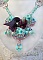 Collier Blue Flowers brod&eacute; avec un ruban de soie framboise/truffe &agrave; laquelle s&rsquo;ajoute : cabochons, perles nacr&eacute;es Rosaline et Ivoire, toupies Jet, anneaux ovales, perles marbr&eacute;es Bleu Ciel et Blanc