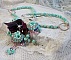 Collier Blue Flowers brod&eacute; avec un ruban de soie framboise/truffe &agrave; laquelle s&rsquo;ajoute : cabochons, perles nacr&eacute;es Rosaline et Ivoire, toupies Jet, anneaux ovales, perles marbr&eacute;es Bleu Ciel et Blanc