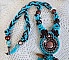 Collier Turquoise Haute Couture au Style Am&eacute;rindien brod&eacute; sur du Cuir avec des cabochons ronds Nacre Acajou et Prune, s&rsquo;ajoute un cabochon Turquoise. Orn&eacute; de cristaux, ruban, perles et rocailles 