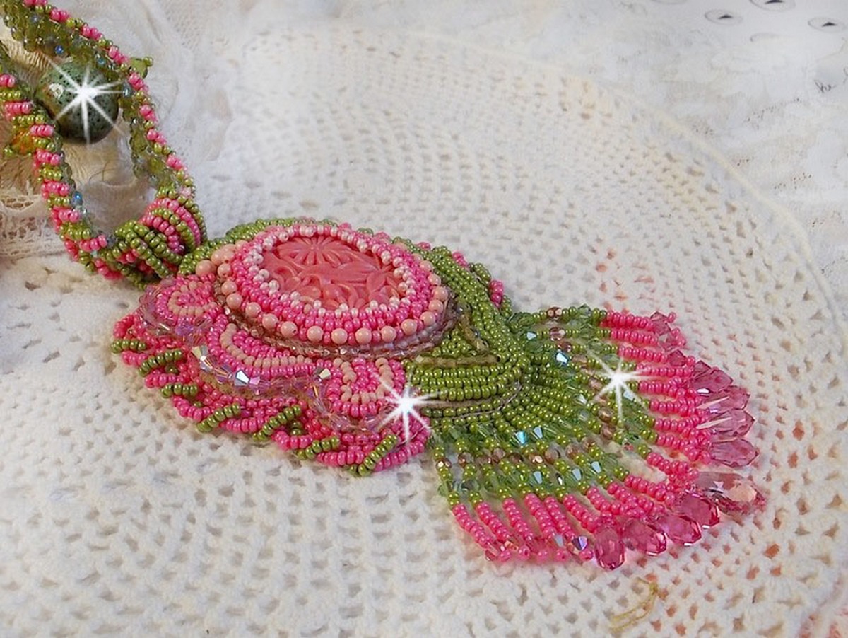 Collier Miss Lady brod&eacute; avec un cabochon repr&eacute;sentant des fleurs de couleur Rose Pink &agrave; laquelle s'ajoute perles rondes, toupies en Cristal, facettes, rocailles Anis, Rose et perle c&eacute;ramique 