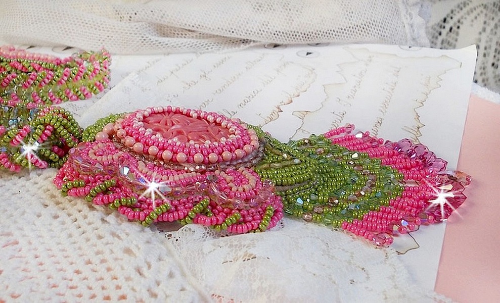 Collier Miss Lady brod&eacute; avec un cabochon repr&eacute;sentant des fleurs de couleur Rose Pink &agrave; laquelle s'ajoute perles rondes, toupies en Cristal, facettes, rocailles Anis, Rose et perle c&eacute;ramique 