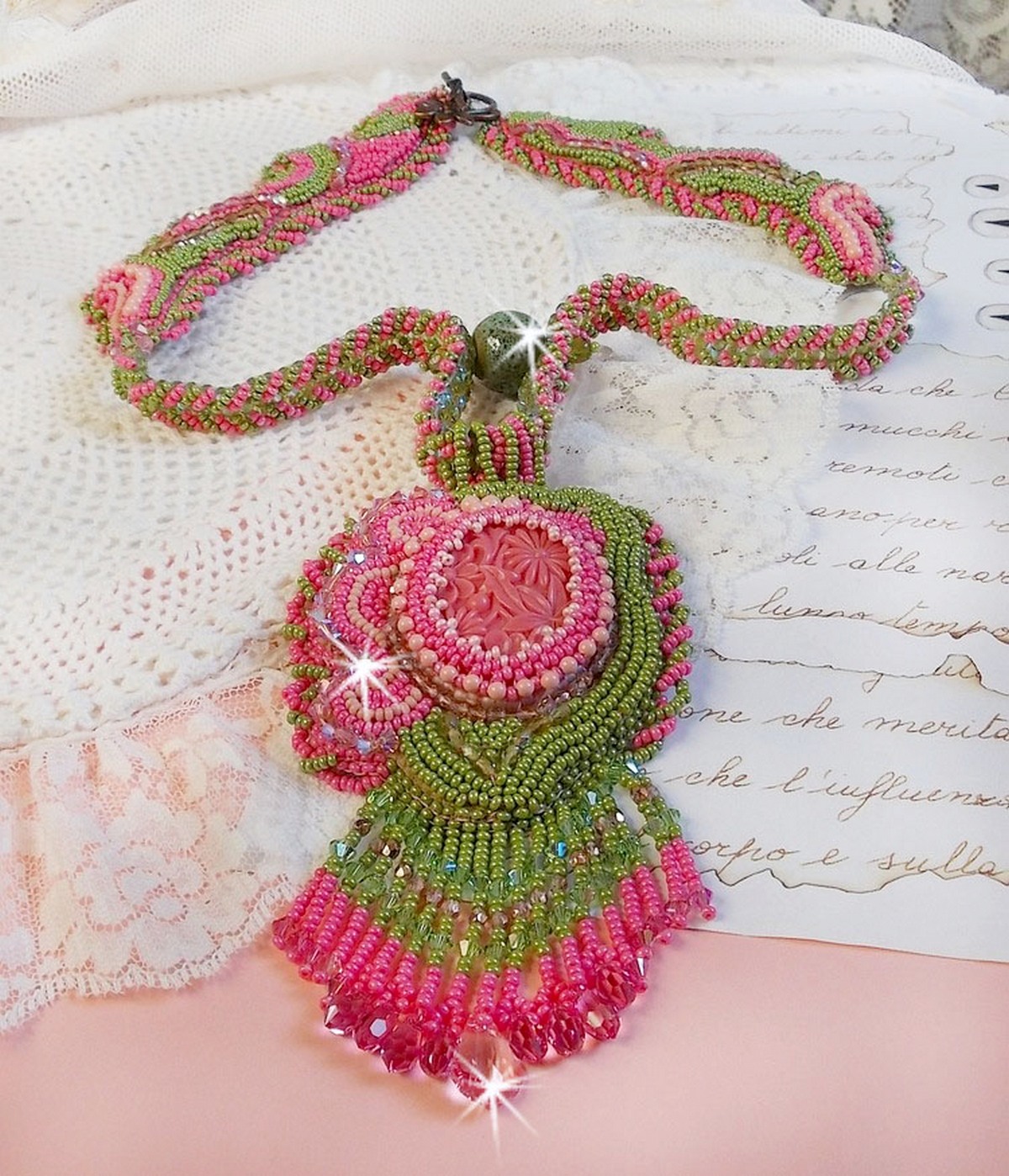 Collier Miss Lady brod&eacute; avec un cabochon repr&eacute;sentant des fleurs de couleur Rose Pink &agrave; laquelle s'ajoute perles rondes, toupies en Cristal, facettes, rocailles Anis, Rose et perle c&eacute;ramique 