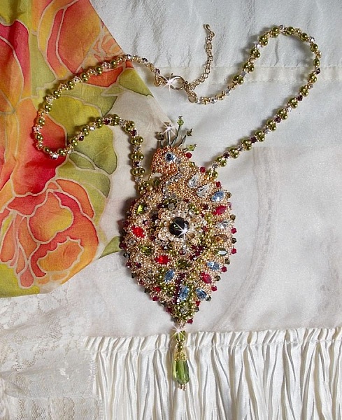 Collier L&rsquo;Oiseau des Iles brod&eacute; fa&ccedil;on Art Nouveau sur une su&eacute;dine avec une estampe o&ugrave; se niche diff&eacute;rents cristaux de tailles et couleurs diff&eacute;rentes, des rocailles Miyuki et des perles Antiques 