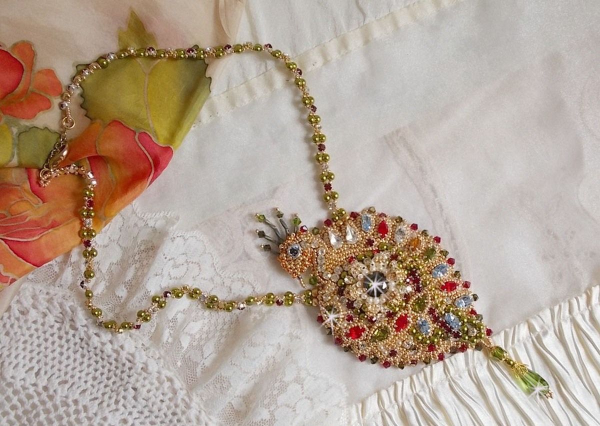 Collier L&rsquo;Oiseau des Iles brod&eacute; fa&ccedil;on Art Nouveau sur une su&eacute;dine avec une estampe o&ugrave; se niche diff&eacute;rents cristaux de tailles et couleurs diff&eacute;rentes, des rocailles Miyuki et des perles Antiques 