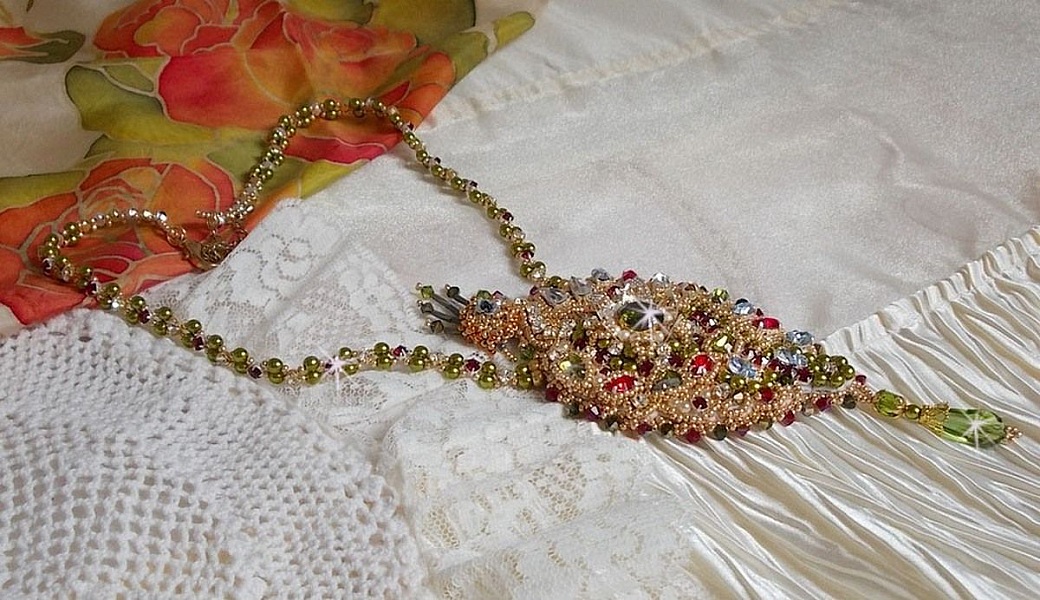 Collier L&rsquo;Oiseau des Iles brod&eacute; fa&ccedil;on Art Nouveau sur une su&eacute;dine avec une estampe o&ugrave; se niche diff&eacute;rents cristaux de tailles et couleurs diff&eacute;rentes, des rocailles Miyuki et des perles Antiques 