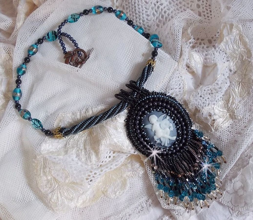 Pendentif Angelot avec un cabochon Ange brod&eacute; de perles rondes nacr&eacute;es Cristal avec des rocailles. S&rsquo;ajoute des facettes, toupies, perles ovales Lampwok serti d&rsquo;un ruban Dor&eacute; et palets