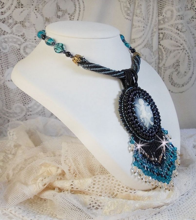 Pendentif Angelot avec un cabochon Ange brod&eacute; de perles rondes nacr&eacute;es Cristal avec des rocailles. S&rsquo;ajoute des facettes, toupies, perles ovales Lampwok serti d&rsquo;un ruban Dor&eacute; et palets