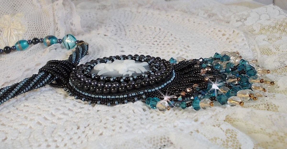 Pendentif Angelot avec un cabochon Ange brod&eacute; de perles rondes nacr&eacute;es Cristal avec des rocailles. S&rsquo;ajoute des facettes, toupies, perles ovales Lampwok serti d&rsquo;un ruban Dor&eacute; et palets