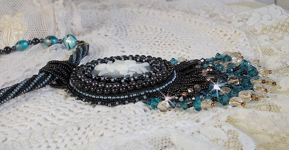 Pendentif Angelot avec un cabochon Ange brod&eacute; de perles rondes nacr&eacute;es Cristal avec des rocailles. S&rsquo;ajoute des facettes, toupies, perles ovales Lampwok serti d&rsquo;un ruban Dor&eacute; et palets