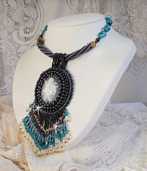 Pendentif Angelot avec un cabochon Ange brod&eacute; de perles rondes nacr&eacute;es Cristal avec des rocailles. S&rsquo;ajoute des facettes, toupies, perles ovales Lampwok serti d&rsquo;un ruban Dor&eacute; et palets