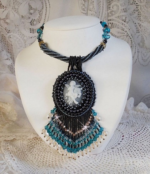 Pendentif Angelot avec un cabochon Ange brod&eacute; de perles rondes nacr&eacute;es Cristal avec des rocailles. S&rsquo;ajoute des facettes, toupies, perles ovales Lampwok serti d&rsquo;un ruban Dor&eacute; et palets