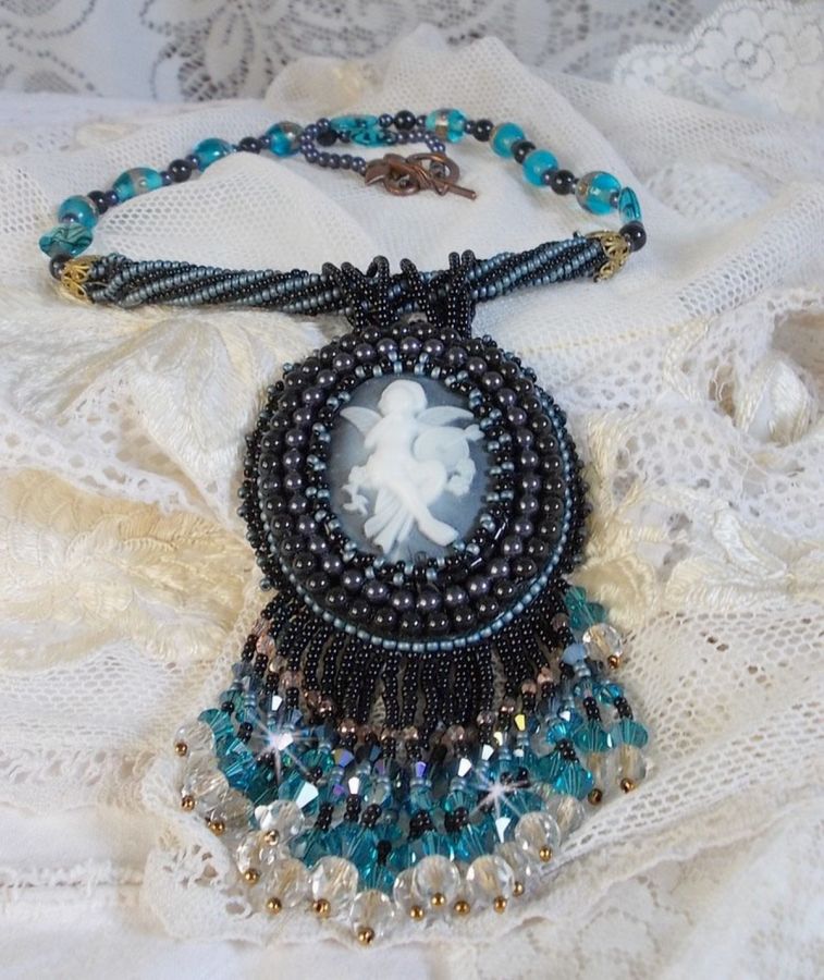 Pendentif Angelot avec un cabochon Ange brod&eacute; de perles rondes nacr&eacute;es Cristal avec des rocailles. S&rsquo;ajoute des facettes, toupies, perles ovales Lampwok serti d&rsquo;un ruban Dor&eacute; et palets
