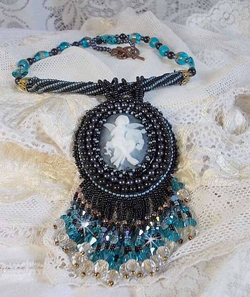 Pendentif Angelot avec un cabochon Ange brod&eacute; de perles rondes nacr&eacute;es Cristal avec des rocailles. S&rsquo;ajoute des facettes, toupies, perles ovales Lampwok serti d&rsquo;un ruban Dor&eacute; et palets