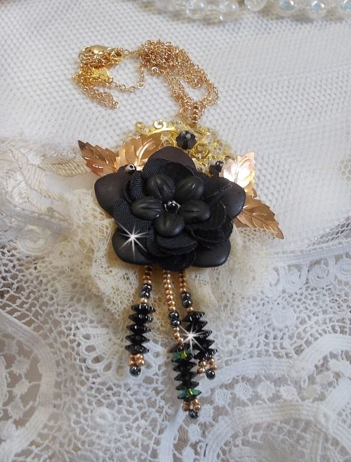 Pendentif Attrapes R&ecirc;ves brod&eacute; avec des fleurs Lucites Noires sur une dentelle Beige et une estampe dor&eacute;e. Les pendants sont des fleurs en cristal avec des rocailles. Mont&eacute; avec une cha&icirc;ne plaqu&eacute; Or