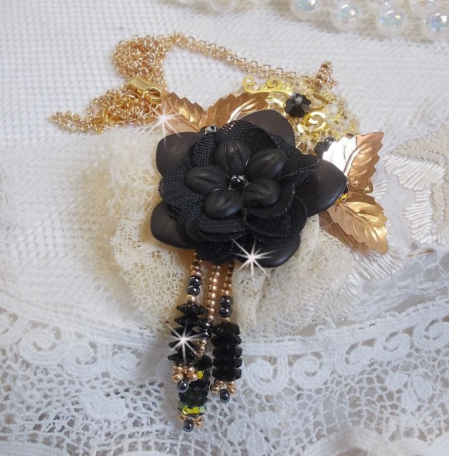 Pendentif Attrapes R&ecirc;ves brod&eacute; avec des fleurs Lucites Noires sur une dentelle Beige et une estampe dor&eacute;e. Les pendants sont des fleurs en cristal avec des rocailles. Mont&eacute; avec une cha&icirc;ne plaqu&eacute; Or