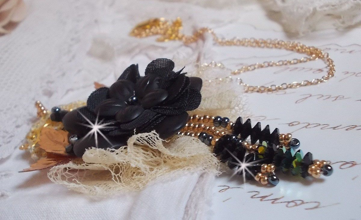 Pendentif Attrapes R&ecirc;ves brod&eacute; avec des fleurs Lucites Noires sur une dentelle Beige et une estampe dor&eacute;e. Les pendants sont des fleurs en cristal avec des rocailles. Mont&eacute; avec une cha&icirc;ne plaqu&eacute; Or