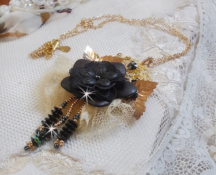 Pendentif Attrapes R&ecirc;ves brod&eacute; avec des fleurs Lucites Noires sur une dentelle Beige et une estampe dor&eacute;e. Les pendants sont des fleurs en cristal avec des rocailles. Mont&eacute; avec une cha&icirc;ne plaqu&eacute; Or