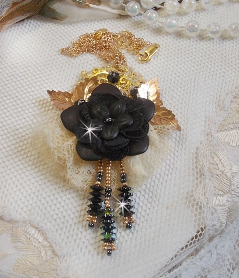 Pendentif Attrapes R&ecirc;ves brod&eacute; avec des fleurs Lucites Noires sur une dentelle Beige et une estampe dor&eacute;e. Les pendants sont des fleurs en cristal avec des rocailles. Mont&eacute; avec une cha&icirc;ne plaqu&eacute; Or