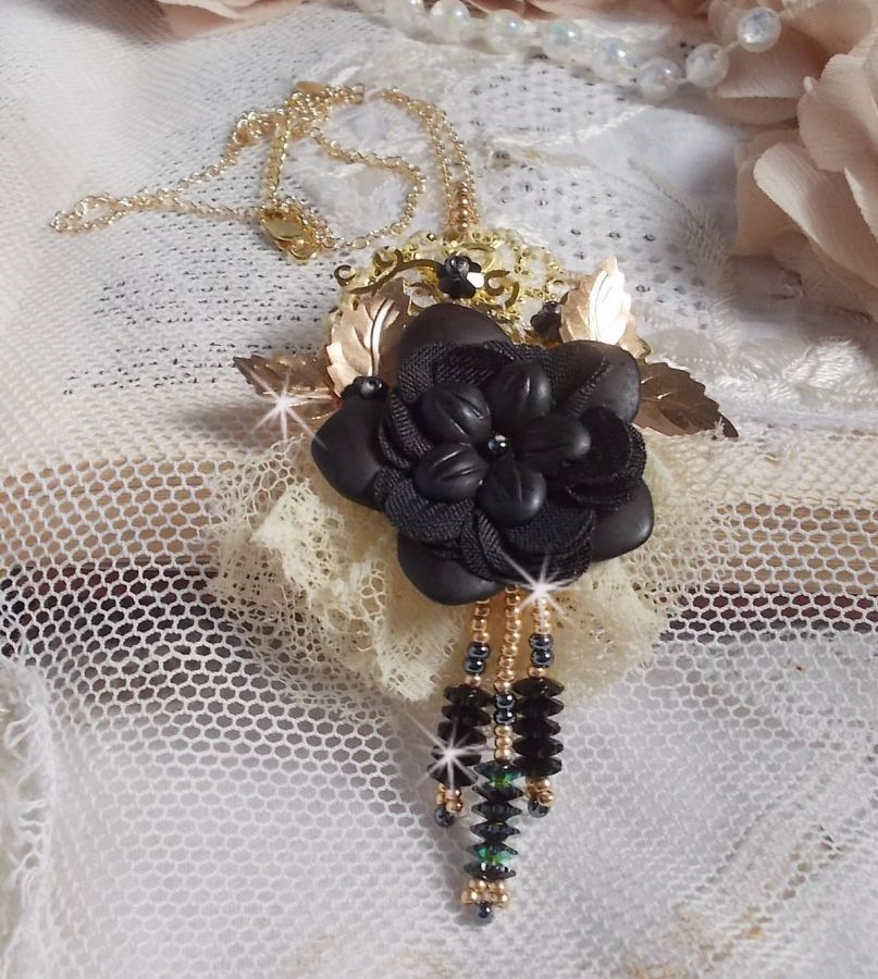 Pendentif Attrapes R&ecirc;ves brod&eacute; avec des fleurs Lucites Noires sur une dentelle Beige et une estampe dor&eacute;e. Les pendants sont des fleurs en cristal avec des rocailles. Mont&eacute; avec une cha&icirc;ne plaqu&eacute; Or