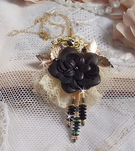 Pendentif Attrapes R&ecirc;ves brod&eacute; avec des fleurs Lucites Noires sur une dentelle Beige et une estampe dor&eacute;e. Les pendants sont des fleurs en cristal avec des rocailles. Mont&eacute; avec une cha&icirc;ne plaqu&eacute; Or