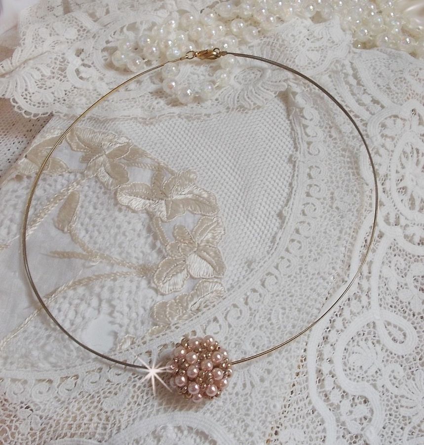 Pendentif Boules nacr&eacute;es avec des perles rondes en cristal de Swarovski de couleur P&ecirc;che et des rocailles en Verre Gold Bronze. Le tour du cou multi rangs est compos&eacute; de 3 rangs fil c&acirc;bl&eacute; en laiton.