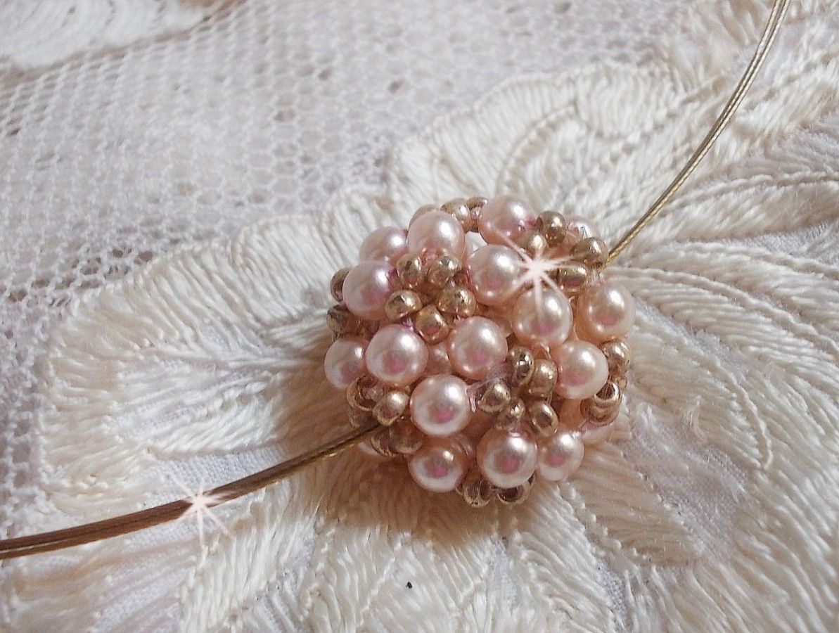 Pendentif Boules nacr&eacute;es avec des perles rondes en cristal de Swarovski de couleur P&ecirc;che et des rocailles en Verre Gold Bronze. Le tour du cou multi rangs est compos&eacute; de 3 rangs fil c&acirc;bl&eacute; en laiton.