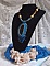 Pendentif Corsica avec un cabochon : une Agate Bleue brod&eacute;e avec des perles nacr&eacute;es Bleu Lapis en cristal &agrave; laquelle s&rsquo;ajoute des rocailles saphir et travertin entrelac&eacute;es pour former une dentelle