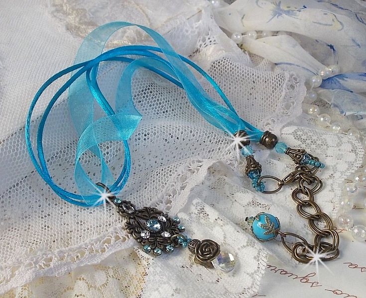 Pendentif Lady in Blue mont&eacute; avec des chandeliers, des cristaux : cabochons, perles rondes et toupies, perles en c&eacute;ramique, cabochons Zirconium, rocailles et rubans. Tout est de couleur Bleu et Bronze