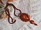 Pendentif artisanal brodé aux perles orange et tons dorés.