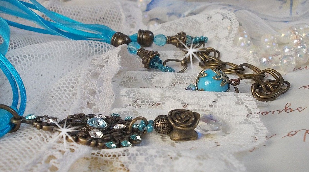Pendentif Lady in Blue mont&eacute; avec des chandeliers, des cristaux : cabochons, perles rondes et toupies, perles en c&eacute;ramique, cabochons Zirconium, rocailles et rubans. Tout est de couleur Bleu et Bronze