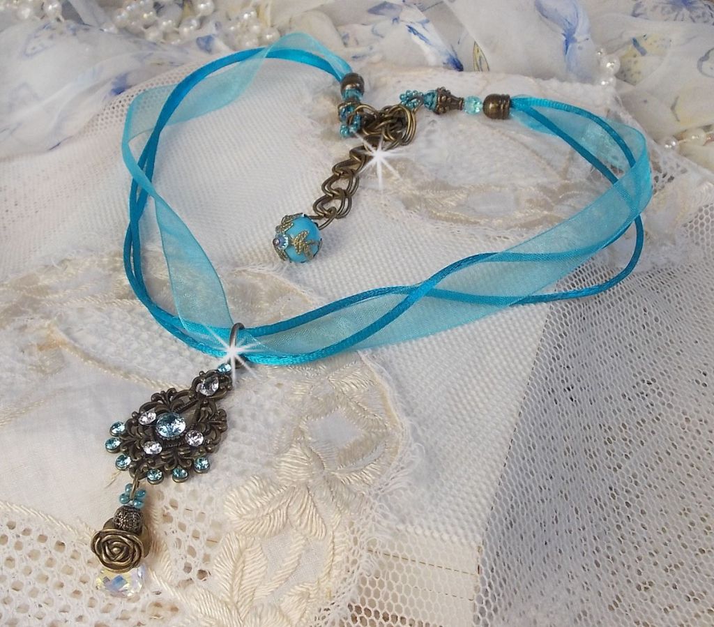 Pendentif Lady in Blue mont&eacute; avec des chandeliers, des cristaux : cabochons, perles rondes et toupies, perles en c&eacute;ramique, cabochons Zirconium, rocailles et rubans. Tout est de couleur Bleu et Bronze